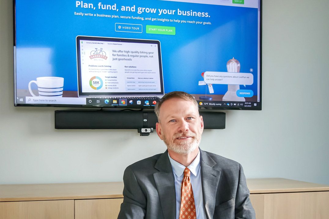 Clemson Small Business Development Center Area Manager Ben Calhoun in front of a monitor displaying LivePlan.