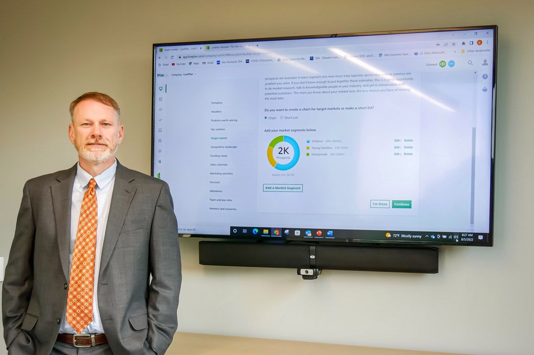 Clemson Small Business Development Center Area Manager Ben Calhoun in front of a monitor displaying LivePlan.