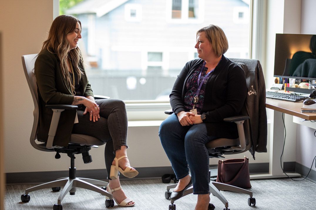 Two Kids FIRST employees chatting about the trajectory of the nonprofit while sitting in the office